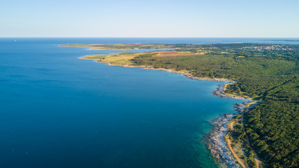 Drone shot of a rocky headland at daylight with emerald color water