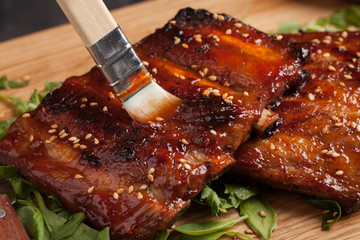 Close-up chef spreading sauce bbq on ribs with brush