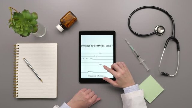 Top View Overhead Of Doctor Examining Patient Information Form On Computer