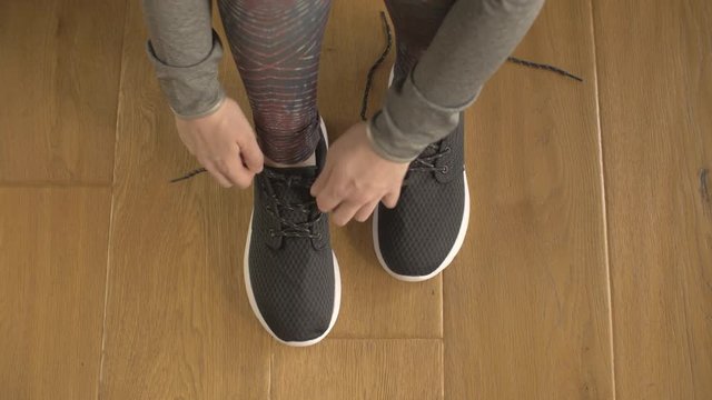Overhead Shot Of Fit Woman Tying Shoelaces On Hardwood Floor