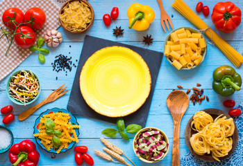 Different types of pasta with various types of vegetables, health or vegetarian concept on a wooden background,  Top view