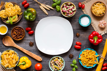 Different types of pasta with various types of vegetables, health or vegetarian concept on a wooden background,  Top view