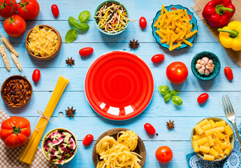 Different types of pasta with various types of vegetables, health or vegetarian concept on a wooden background,  Top view