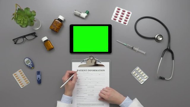 Overhead Top View Of Female Doctor Filling Patient Information Form
