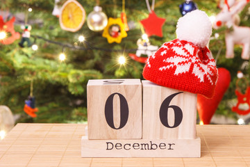 Date 6 December with cap and festive tree with decoration in background, Christmas time concept
