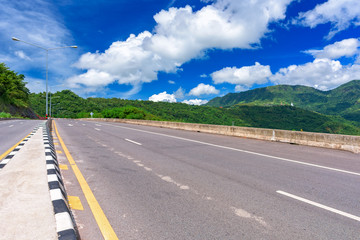 Asphalt road and mountains landscape under morning sky with clouds