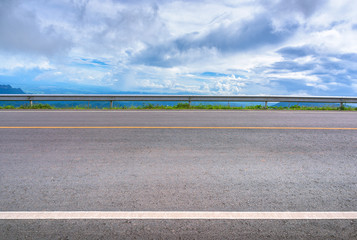 Asphalt road and mountains landscape under morning sky with clouds