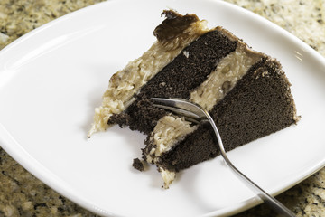 German chocolate cake on a square white plate with a fork in the cake
