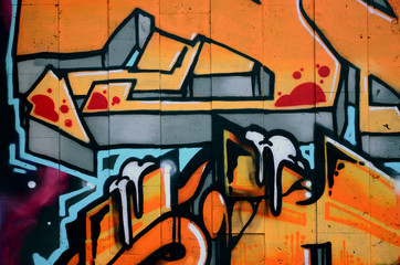 A fragment of detailed graffiti of a drawing made with aerosol paints on a wall of concrete tiles. Background image of street art in warm red color tones