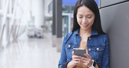 Woman looking at cellphone for time flight at Hong Kong airport