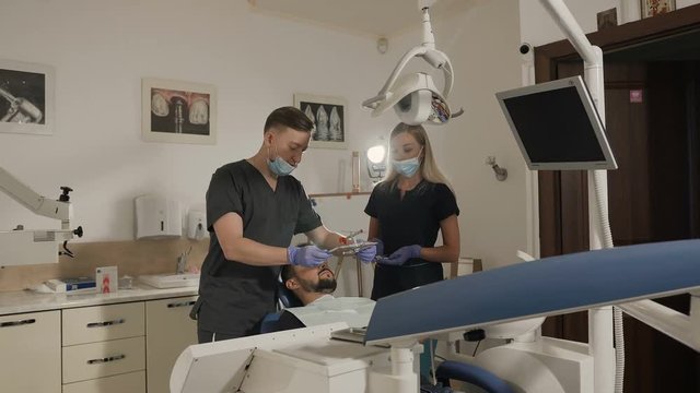 The dentist and his assistant use face bow while treating the patient's teeth