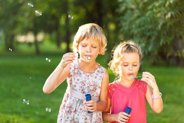 Portrait of Two Little Girlfriends / Sisters Blowing Bubbles