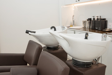 two leather armchairs with white wash basins in  beauty salon close up