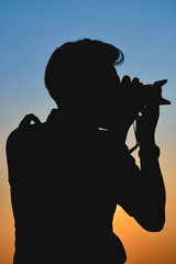 Male photographer shooting. Silhouette style