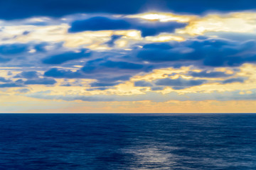 Fototapeta premium Stylized abstract landscape seascape sunset long exposure with clouds under different shades of blue, orange, yellow and red.