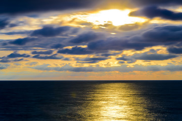 Stylized abstract landscape seascape sunset long exposure with clouds under different shades of blue, orange, yellow and red.