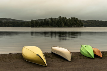 Canada Ontario Lake two rivers grey morning dark atmosphere Canoe Canoes parked beach water in Algonquin National Park