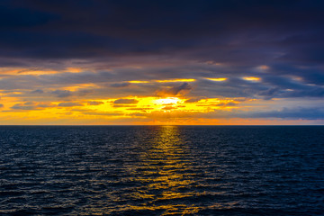 Stylized abstract landscape seascape sunset long exposure with clouds under different shades of blue, orange, yellow and red.