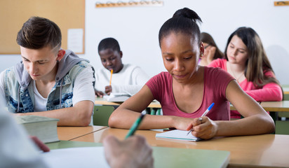 Enthusiastic girls and boys taking the notes while