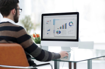 businessman analyzing graphs on computer at desk