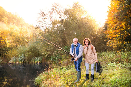 Senior Couple Fishing At The Lake In Autumn.