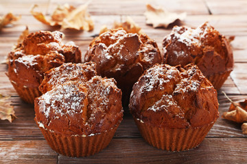 Tasty muffin with dry leafs on brown wooden table