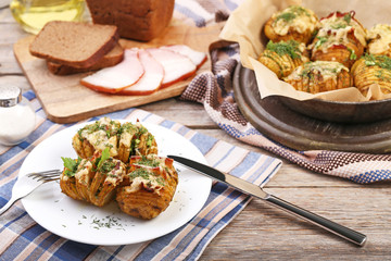Baked potato with cheese and bacon in plate on wooden table