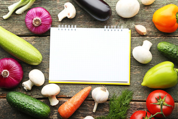 Blank recipe book with vegetables on wooden table