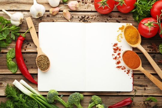 Blank recipe book with vegetables on wooden table