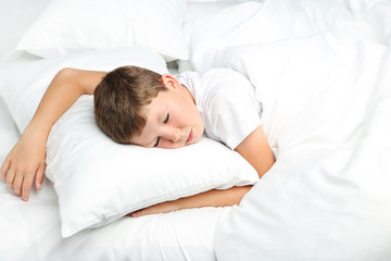 Fototapeta na wymiar Young boy sleeping in white bed