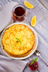 Stack of thin pancakes, crepes on white plate. View from above, top studio shot, vertical