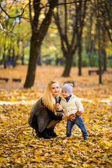 Fototapeta premium Happy family having fun outdoors in autumn park against yellow leaves background