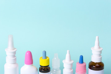 Nasal drops and a nose spray for the treatment of a common cold. Bottles and vials of medicines on a green background. What treatment to choose? Copy space for text