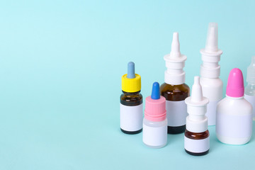 Nasal drops and a nose spray for the treatment of a common cold. Bottles and vials of medicines on a green background. Copy space for text