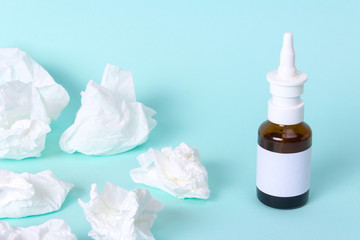 Nasal spray and used paper handkerchiefs cure cold. Glass bottle with medicine on a green background