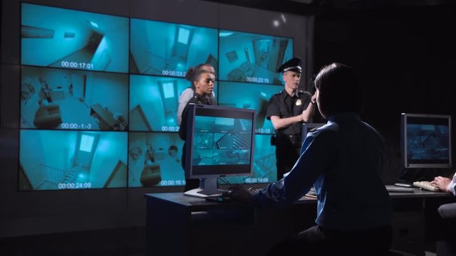 Group of male and female police and security specialists receive a robbery alarm on their closed circuit camera monitors