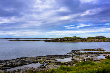 A calming Ocean Vista with a gorgeous cloudscape and rocky island formations in the background and tide pools in the foreground.  