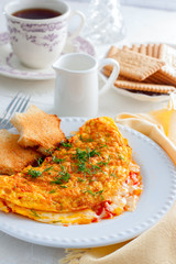 Breakfast with an omelette with tomatoes and cheese, tea and biscuits, selective focus
