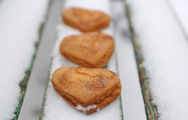 Homemade cookies with sugar and cinnamon in the form of hearts on a background of snow