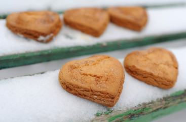 Homemade cookies with sugar and cinnamon in the form of hearts on a background of snow