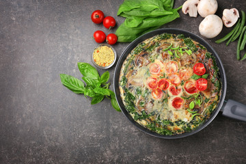 Frying pan with delicious spinach frittata on dark background