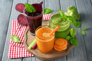 Glasses with different vegetable smoothies on wooden board