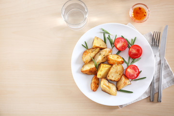 Composition with plate of delicious rosemary potatoes on table