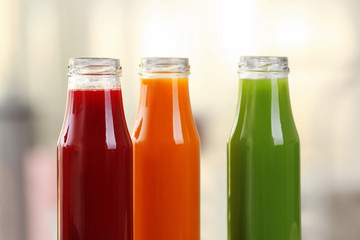 Bottles with various fresh juices on blurred background