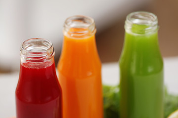 Bottles with various fresh juices on blurred background