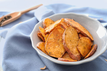 Bowl with yummy sweet potato chips on table