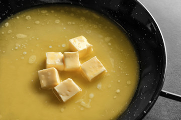 Frying pan with melting butter on grey background, closeup