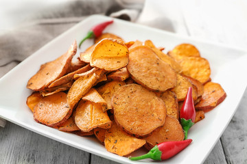 Plate with yummy sweet potato chips on table