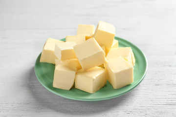 Plate with cubes of butter on light background