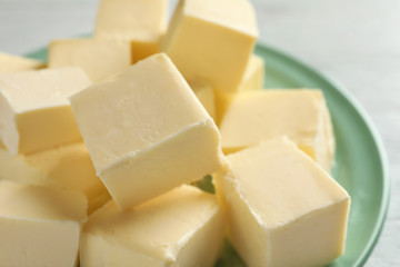 Plate with cubes of butter on light background
